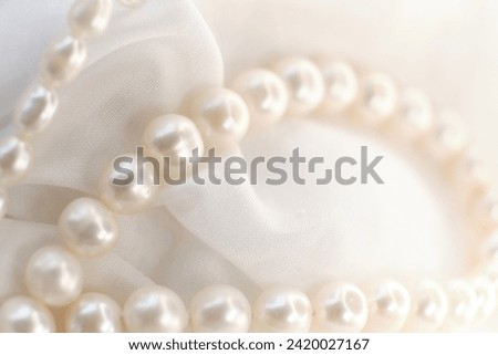 The gentle curve of a pearl string on a white cloth evokes a sense of serene elegance. It's a silent ode to nature's irreplaceable aesthetics amidst the clamor for the modern and synthetic. Royalty-Free Stock Photo #2420027167