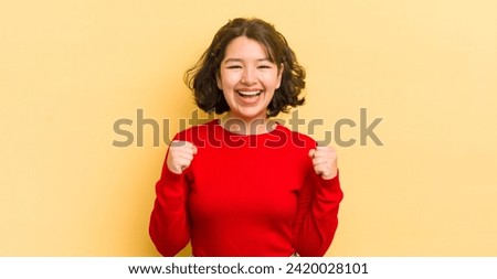 pretty hispanic woman feeling shocked, excited and happy, laughing and celebrating success, saying wow!