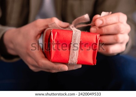  close-up Man's hands opening a Valentine's gift with a bow.