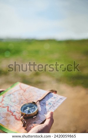 Close-up of a tourist hand holding a compass - stock photography concepts. A male hand, a tourist adventurer hiker uses map and compass to plot course. Copy Advertising space. Tour tourism