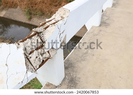 Broken concrete bridge railing. Closeup of the edge of a white cement bridge over an irrigation canal that has cracked due to an accident can be dangerous for users. Selective focus Royalty-Free Stock Photo #2420067853