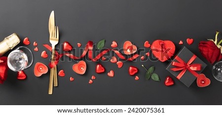 Beautiful romantic table setting with wine, roses and gifts on black background. Romantic dinner. Valentine's Day. Top view, flat lay, copy space