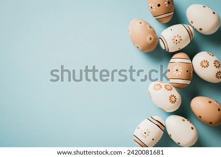 Stylish Easter card. Flat lay brown and white Easter eggs decorated floral print on light blue background. Top view with copy space.