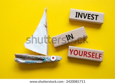 Invest in Yourself symbol. Concept words Invest in Yourself on wooden blocks. Beautiful yellow background with boat. Business and Invest in Yourself concept. Copy space.