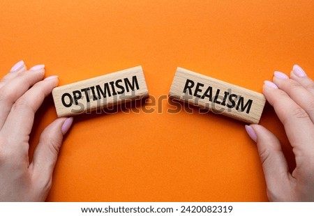 Optimism or Realism symbol. Concept word Optimism or Realism on wooden blocks. Businessman hand. Beautiful orange background. Business and Optimism or Realism concept. Copy space