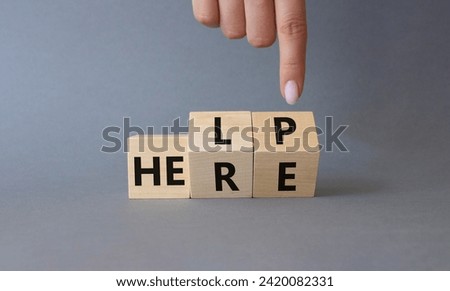 Help is here symbol. Businessman hand points at cube with words Here to Help. Beautiful grey background. Business and Help is here concept. Copy space Royalty-Free Stock Photo #2420082331