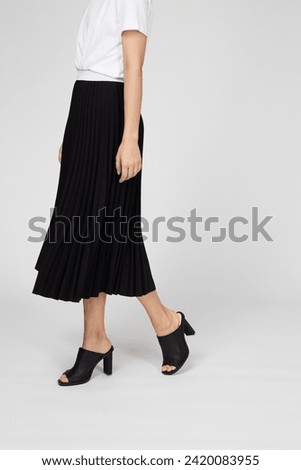 Black women's luxury Classic Long Maxi pleated skirt on model isolated on white background. Woman wearing Midi folded Accordion Skirt, summer autumn outfit. Side view. Template, concept Royalty-Free Stock Photo #2420083955