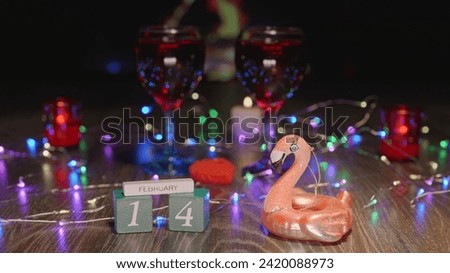 Saint Valentine's Day. Video postcard. Two glasses of wine. Cozy atmosphere with fireplace, plaid, garland and candles. Love, hearts,  passion and pink flamingo.