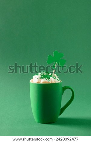 Irish coffee in green cup with whipped cream and sprinkles for St Patricks Day on green background. Vertical format. Close up. Copy space.