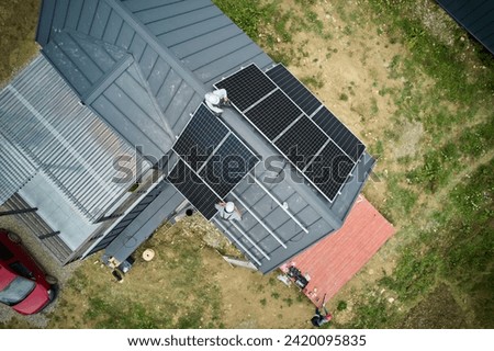 Builders building photovoltaic solar module station on roof of house. Men electricians in helmets installing solar panel system outdoors. Concept of alternative and renewable energy. Aerial view.