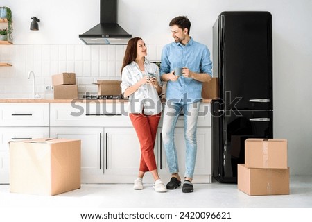 Young family couple moving new apartment, standing on modern kitchen with cup of coffee and talking about furnishing room and design interior. Home settling concept Royalty-Free Stock Photo #2420096621