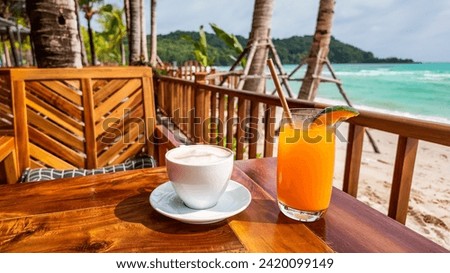 A refreshing coffee and juice served on a beachside cafe table with a tropical ocean view, encapsulating a serene vacation concept Royalty-Free Stock Photo #2420099149