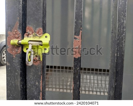 photo of small door bolt. lock on an iron fence