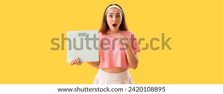 Surprised young woman holding scales on yellow background. Weight loss concept Royalty-Free Stock Photo #2420108895