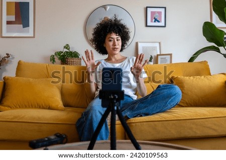 Young african american mixed race woman recording video talking to followers during live stream on social media. Female content creator using phone to communicate with subscribers. Technology concept. Royalty-Free Stock Photo #2420109563