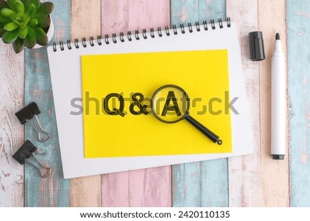 a magnifying glass hones in on an text Q and A. the yellow background signifies attention and urgency. spotlight on urgency. Royalty-Free Stock Photo #2420110135