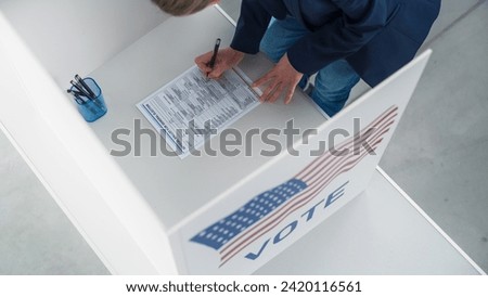 Top Down Footage of a Female Filling Out a Paper Ballot in a Voting Booth on the Day of National Elections in the United States of America. Anonymous Woman Voting for Elected Officials Royalty-Free Stock Photo #2420116561