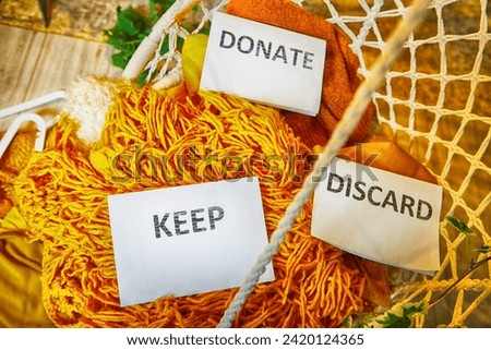 Signs with the words keep, donate, discard and fashion clothes folded in stacks in cozy room. The concept of cluttering and decluttering. Background