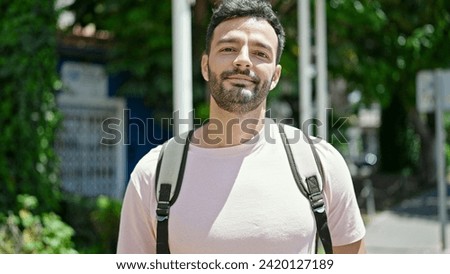 Young hispanic man tourist wearing backpack relaxed at park Royalty-Free Stock Photo #2420127189