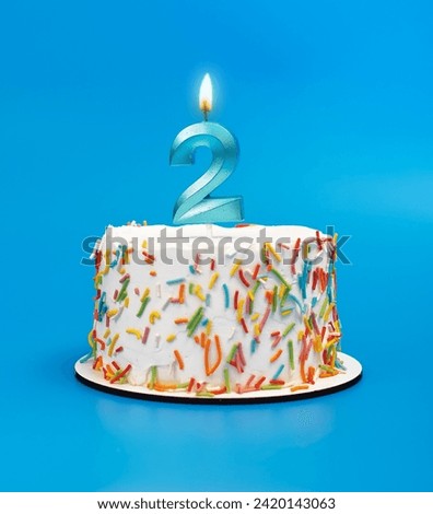 2 shaped candle light on happy birthday cake on blue