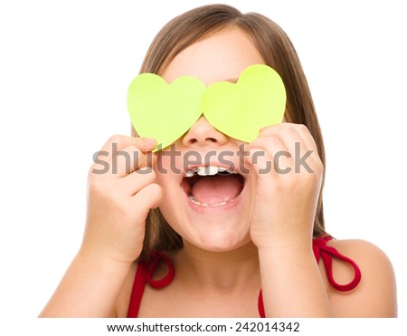 Little girl is holding hearts over her eyes, valentine concept, isolated on white