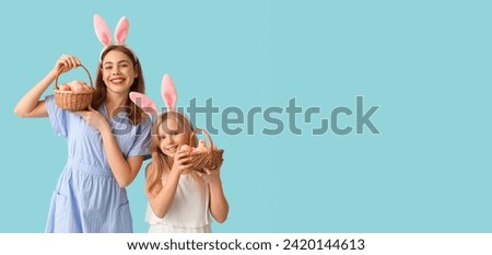 Happy mother and her little daughter with Easter baskets on light blue background with space for text Royalty-Free Stock Photo #2420144613