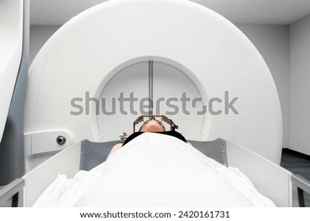 The patient lies in front of the device for the treatment of cancer with a gamma knife. She has a metal clip cap on his head. Gamma Knife stereotactic radiosurgery. Royalty-Free Stock Photo #2420161731