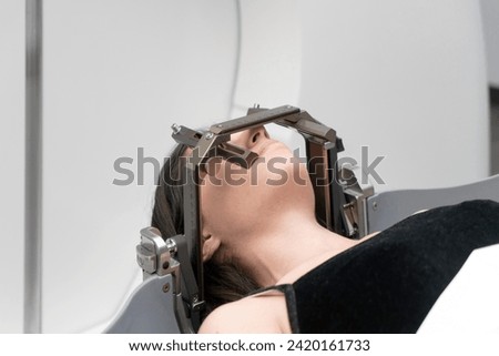 The patient lies in front of the device for the treatment of cancer with a gamma knife. She has a metal clip cap on his head. Gamma Knife stereotactic radiosurgery. Royalty-Free Stock Photo #2420161733