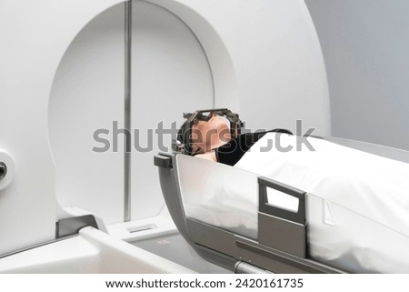 The patient lies in front of the device for the treatment of cancer with a gamma knife. She has a metal clip cap on his head. Gamma Knife stereotactic radiosurgery. Royalty-Free Stock Photo #2420161735