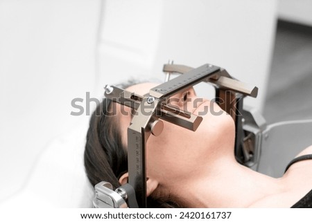The patient lies in front of the device for the treatment of cancer with a gamma knife. She has a metal clip cap on his head. Gamma Knife stereotactic radiosurgery. Royalty-Free Stock Photo #2420161737