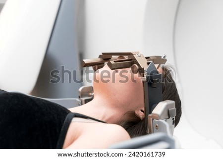 The patient lies in front of the device for the treatment of cancer with a gamma knife. She has a metal clip cap on his head. Gamma Knife stereotactic radiosurgery. Royalty-Free Stock Photo #2420161739