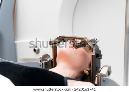 The patient lies in front of the device for the treatment of cancer with a gamma knife. She has a metal clip cap on his head. Gamma Knife stereotactic radiosurgery. Royalty-Free Stock Photo #2420161741