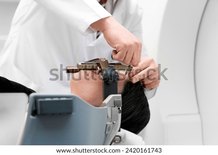 The patient lies in front of the device for the treatment of cancer with a gamma knife. She has a metal clip cap on his head. Gamma Knife stereotactic radiosurgery. Royalty-Free Stock Photo #2420161743