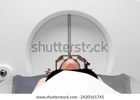 The patient lies in front of the device for the treatment of cancer with a gamma knife. She has a metal clip cap on his head. Gamma Knife stereotactic radiosurgery. Royalty-Free Stock Photo #2420161745