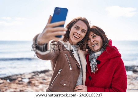 Two women mother and daughter make selfie by smartphone at seaside
