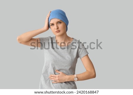 Young woman after chemotherapy suffering from pain on light background. Stomach cancer concept