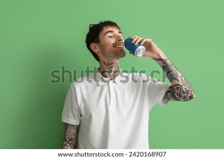 Happy young man with can of soda on green background