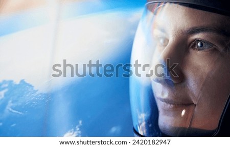 Close up view of woman in glassed space helmet against blue background.