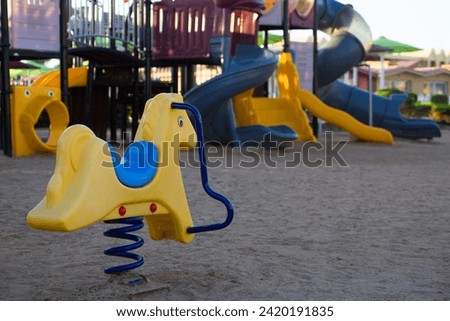 Spring horse made of plastic on a playground for children. Empty space for children to play on the sand outdoors