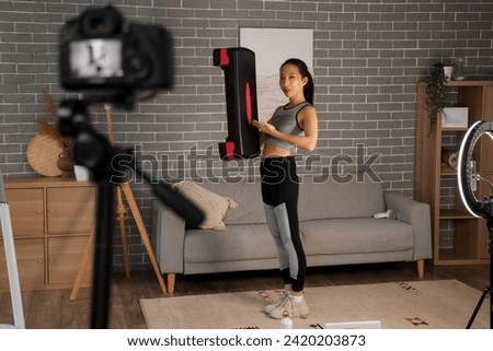 Female Asian sports blogger with stepper recording training video at home