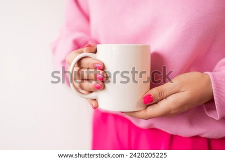 Female hands holding white mug mockup for sublimation presentation design. Pink manicure, pink sweatshirt, trendy color. stock photos of white coffee mug in female hands for designers