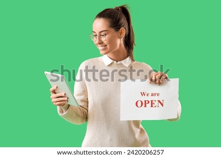Female seller with OPEN sign and tablet computer on green background