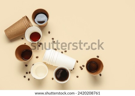 Paper cups of hot coffee and beans on beige background Royalty-Free Stock Photo #2420208761