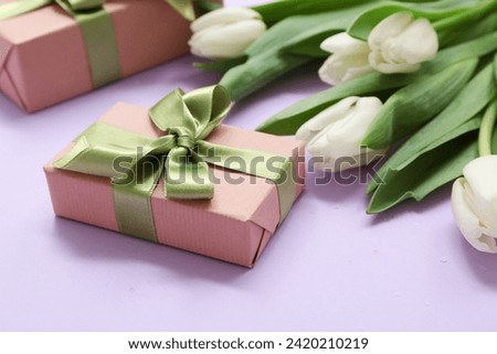 Gift boxes and bouquet of beautiful white tulips on lilac background. International Women's Day