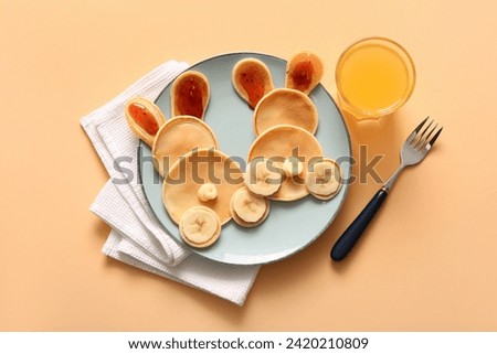 Funny Easter bunny pancakes with glass of juice on orange background