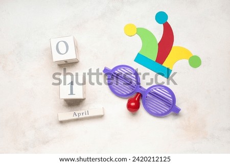 Date of April Fool's Day, funny disguise and paper hat on white background