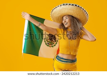 Mature woman in sombrero hat with flag on yellow background. Mexico's Day of the Dead (El Dia de Muertos) celebration Royalty-Free Stock Photo #2420212213
