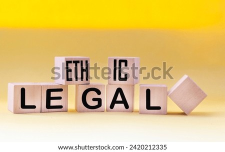 Ethical legal symbol. The words Ethical and Legal on wooden blocks and a beautiful yellow background. Business and ethical or legal concept. Copy space.