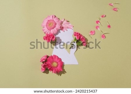 A woman made of paper decorated against pastel background with a lot of flowers and petals. The flowers are arranged as if the woman is holding a bouquet and the petals are flying