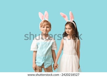Cute little children in bunny ears holding hands on blue background
